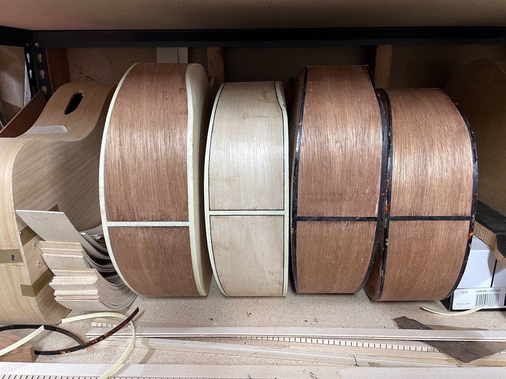 Completed guitar bodies on a shop shelf, assembled and waiting for finish