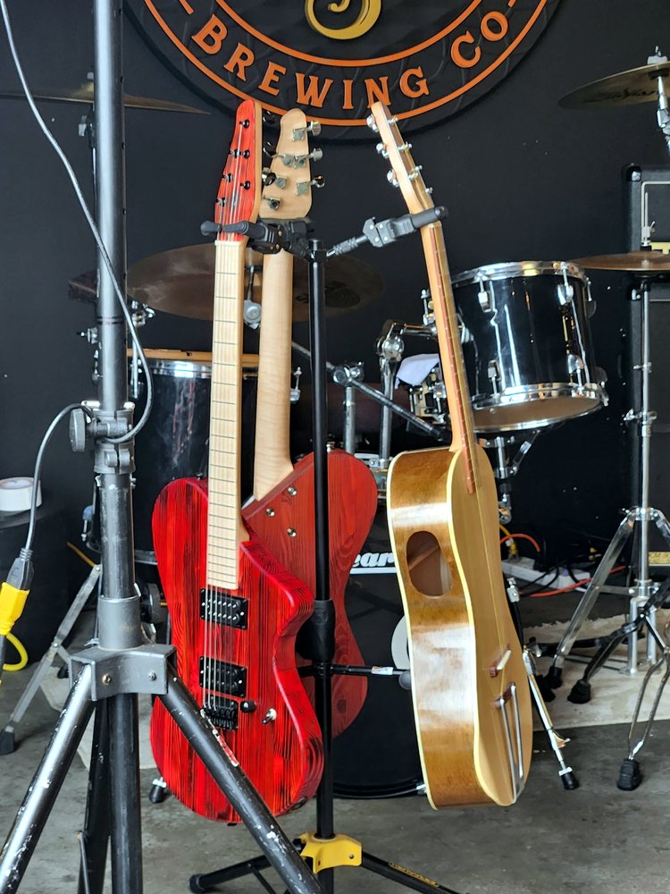 Three finished BLG guitars on stands at a live venue